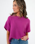 Whatever The Weather Orchid Sleeveless Sweater in vibrant purple with ribbed crew neck, styled with high-waisted denim. Lightweight knit top for layering.