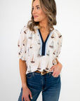 Woman wearing a white blouse with sailboat pattern and blue jeans on a white background
