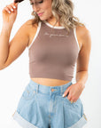 In Your Dreams Brown Cropped Tank Top with cream contrast hem, styled with denim shorts and a brown cap for a trendy summer look.