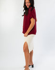 Side view of Burgundy Short Sleeve Blouse and cream ribbed skirt with slit, offering a chic and comfortable outfit for gameday or casual outings.