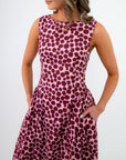 Woman wearing a sleeveless dress with a purple polka dot pattern on a white background