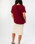 Back view of Burgundy Short Sleeve Blouse highlighting its loose fit and soft fabric, styled with a cream midi skirt for a cozy fall look.