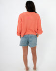 Back view of Papaya Short Sleeve Crop Sweater in coral, styled with denim shorts. Lightweight cropped knit ideal for summer outfits.