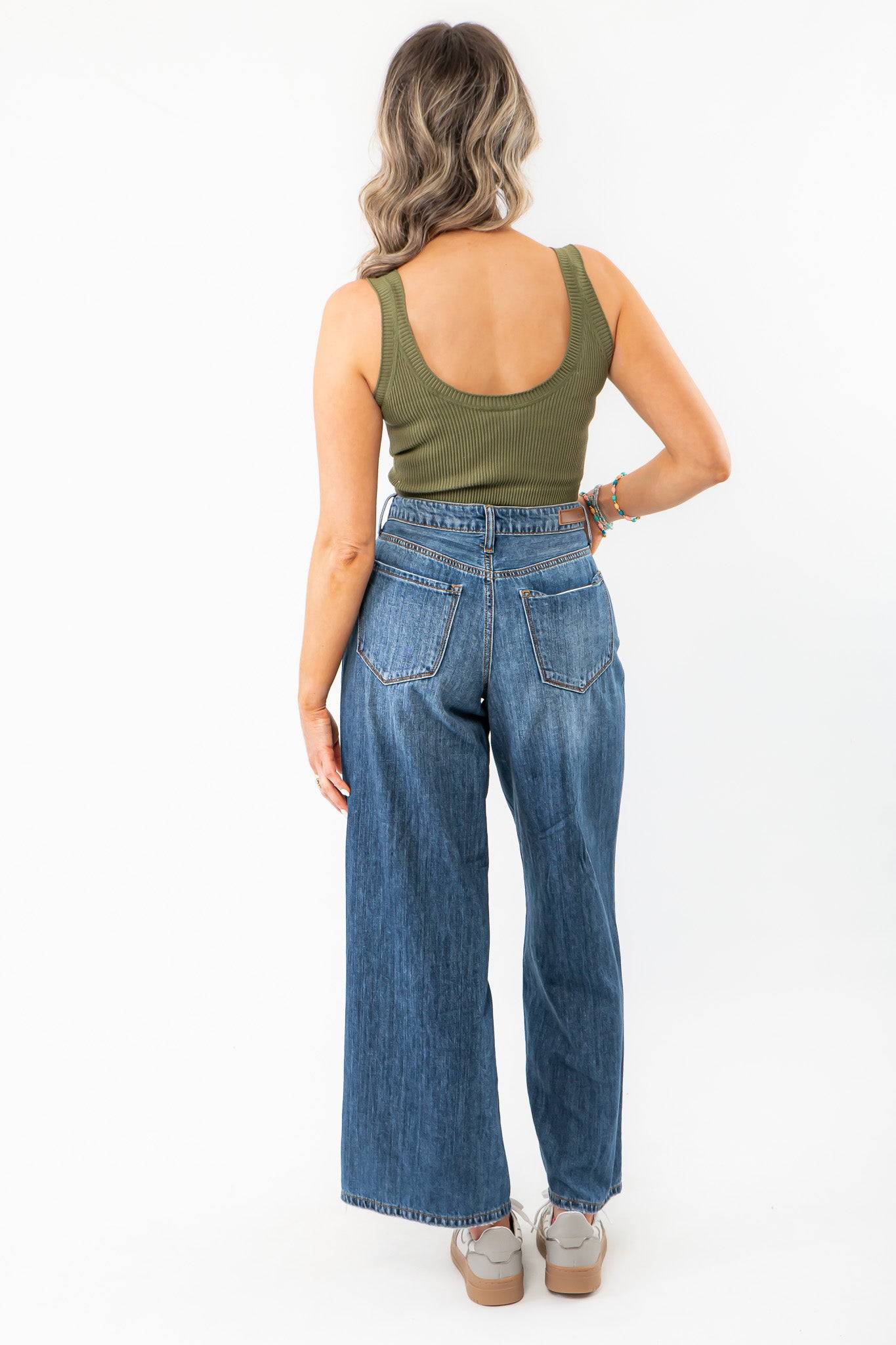 Back view of Olive Seamless Cropped Brami, a ribbed olive green activewear top paired with high-waisted wide-leg jeans. A summer essential for layering.