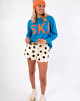 Cozy & stylish Hit The Slopes Blue & Orange Ski Sweater paired with cream polka dot shorts and ankle boots, perfect for winter adventures.