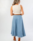 Rear full-body view of Washed Denim Paneled Midi Skirt styled for fall with a sleeveless top and tan heeled boots.