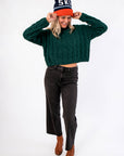 Cozy forest green Tree Farm Stroll Cable-Knit Sweater paired with wide-leg black jeans and brown boots, perfect for festive winter outings.