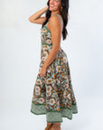 Side view of Tomorrow Is Calling Brown Floral Sleeveless Midi Dress featuring smocked back, flowy fit, and wedge sandals.