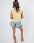 Back view of sleeveless yellow lobster embroidered sweater paired with denim shorts. A relaxed coastal knit for warm-weather wear.