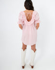 Back view of Show Me Your Mumu Pink Eyelet Toulouse Dress with open back tie detail and ruffled trim, styled for a chic summer outfit.