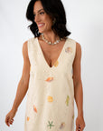 Close-up of woman wearing Coastline Romance beach patterned shift dress with shell and starfish print, styled with shell necklace.