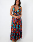 Woman in vibrant tropical print halter maxi dress with tie-back