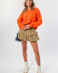 Soft and vibrant Orange Knit Crop Sweater styled with tan ruffle skirt and cream boots, showcasing cozy fall fashion essentials.