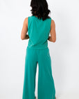 Side view of women in teal lounge set with relaxed fit and beige slide sandals