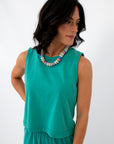 Back view of woman in bright teal sleeveless top, casual summer clothing