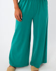Close-up of teal lounge pants with elastic waistband and wide-leg fit