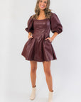 Holiday-ready Bordeaux Bliss Faux Leather Dress featuring side pockets, puff sleeves, and a flattering fit-and-flare silhouette.