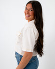 Back view of white denim contrast stitch short sleeve top with model smiling