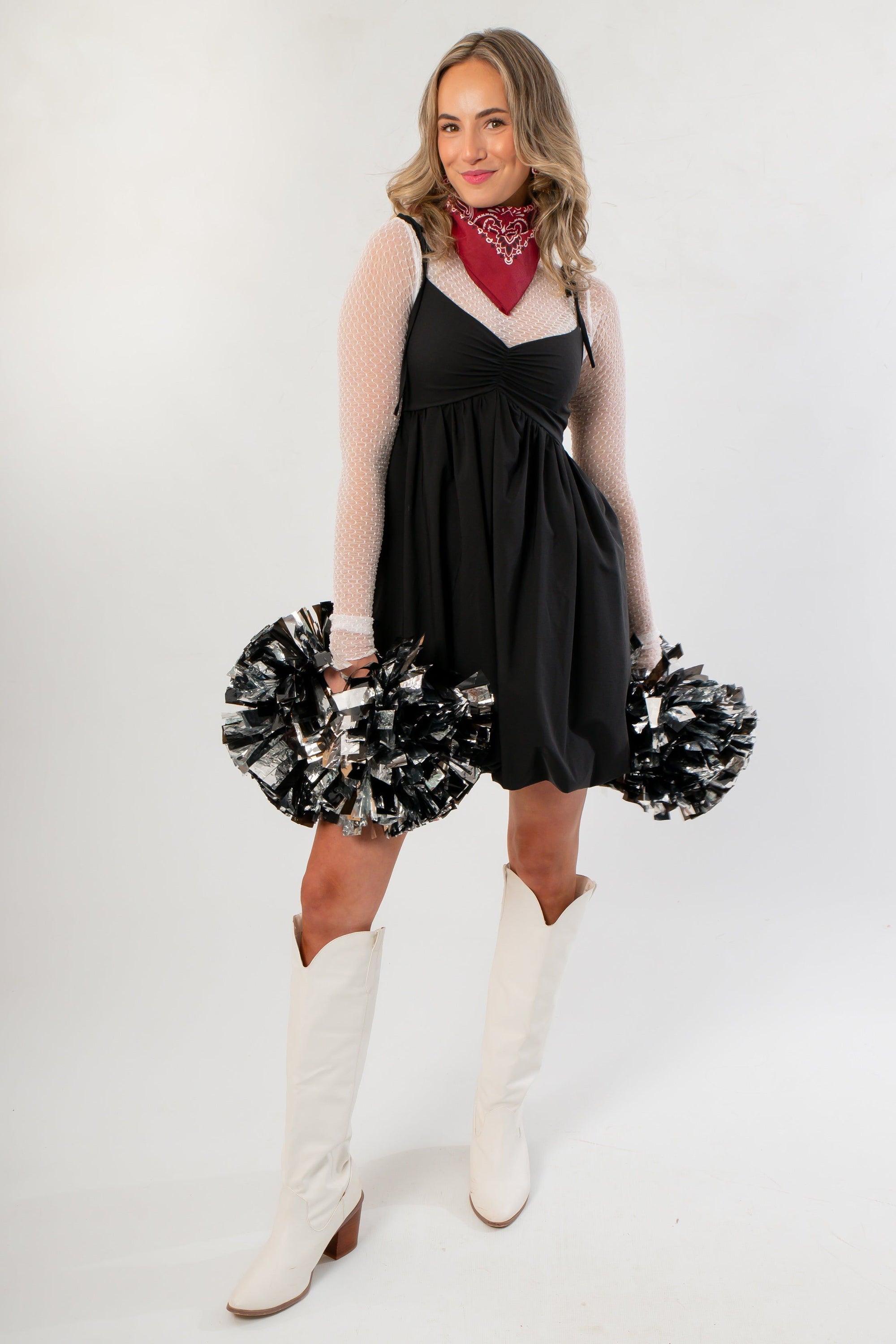 Black Hem Mini Dress styled with white boots and pom-poms, featuring a bubble hem and layered mesh sleeves for a trendy gameday look.