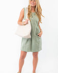 Breezy sage green tank romper styled with a woven tote and sandals, ideal for beach days and summer adventures.