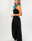 Elegant black strapless linen midi dress with flowy silhouette, styled for casual wear with silver boots and teal scarf from the WM collection.