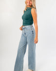 RD Style Funnel Neck Top in green with ruched detailing, styled with wide-leg denim. A sleeveless, sleek tank ideal for casual or work wear.