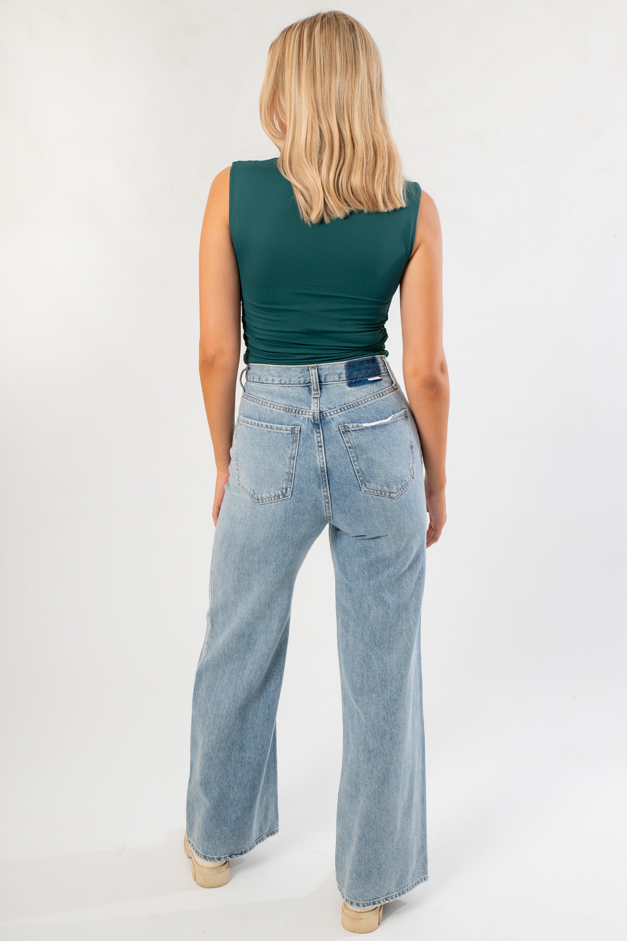 Back view of the Luck Of The Draw Green Ruched Funnel Neck Tank showing smooth fit and sleeveless cut. Styled with light wash wide-leg jeans.