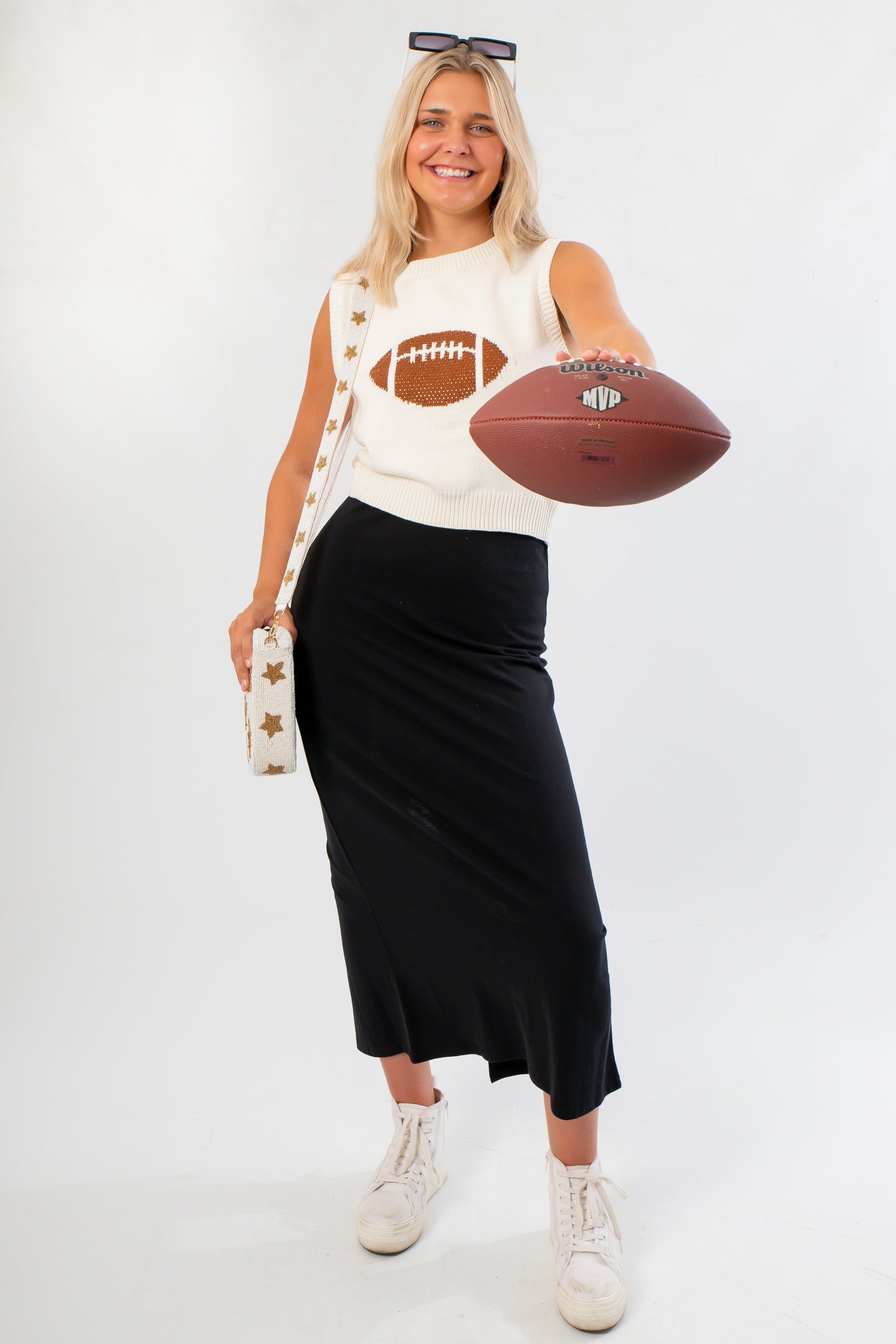 Ned Bedazzled Football Sweater in sleeveless white knit with rhinestone football graphic, styled for game day with black skirt and sneakers.