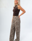 Side view of Luck Of The Draw Brown Ruched Funnel Neck Tank – Sleek Fit paired with leopard print trousers, highlighting the ruched detailing.
