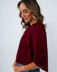Women’s dressy burgundy top for fall with cape sleeves and a shirred neckline for date night, workwear, and game day