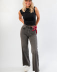Model wearing Luck Of The Draw Black Ruched Funnel Neck Tank – Sleek Fit with high-waisted grey jeans, perfect for gameday or casual fall looks.
