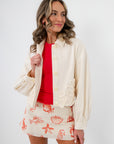 Seagarden Appliqué Floral Detail Jacket in ecru with textured floral appliqué, styled over a red top and printed mini skirt for spring layering.