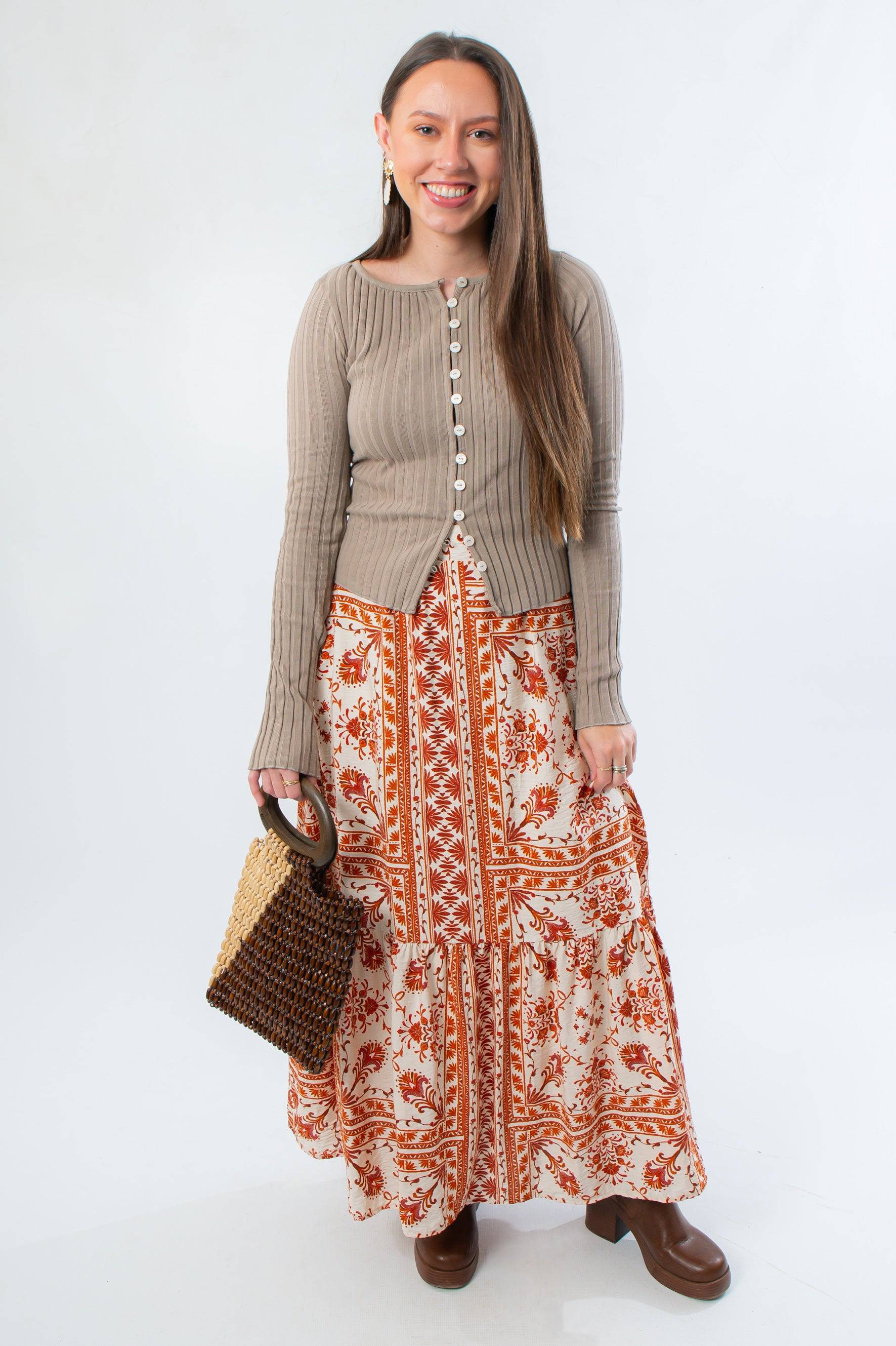 Burnt Orange Floral Patterned Midi Skirt paired with neutral top and woven handbag. A stylish fall outfit for seasonal transitions.