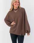 Camden Brown Ribbed Knit Mockneck Top with oversized fit and balloon sleeves, styled with black leggings for a cozy layered look.