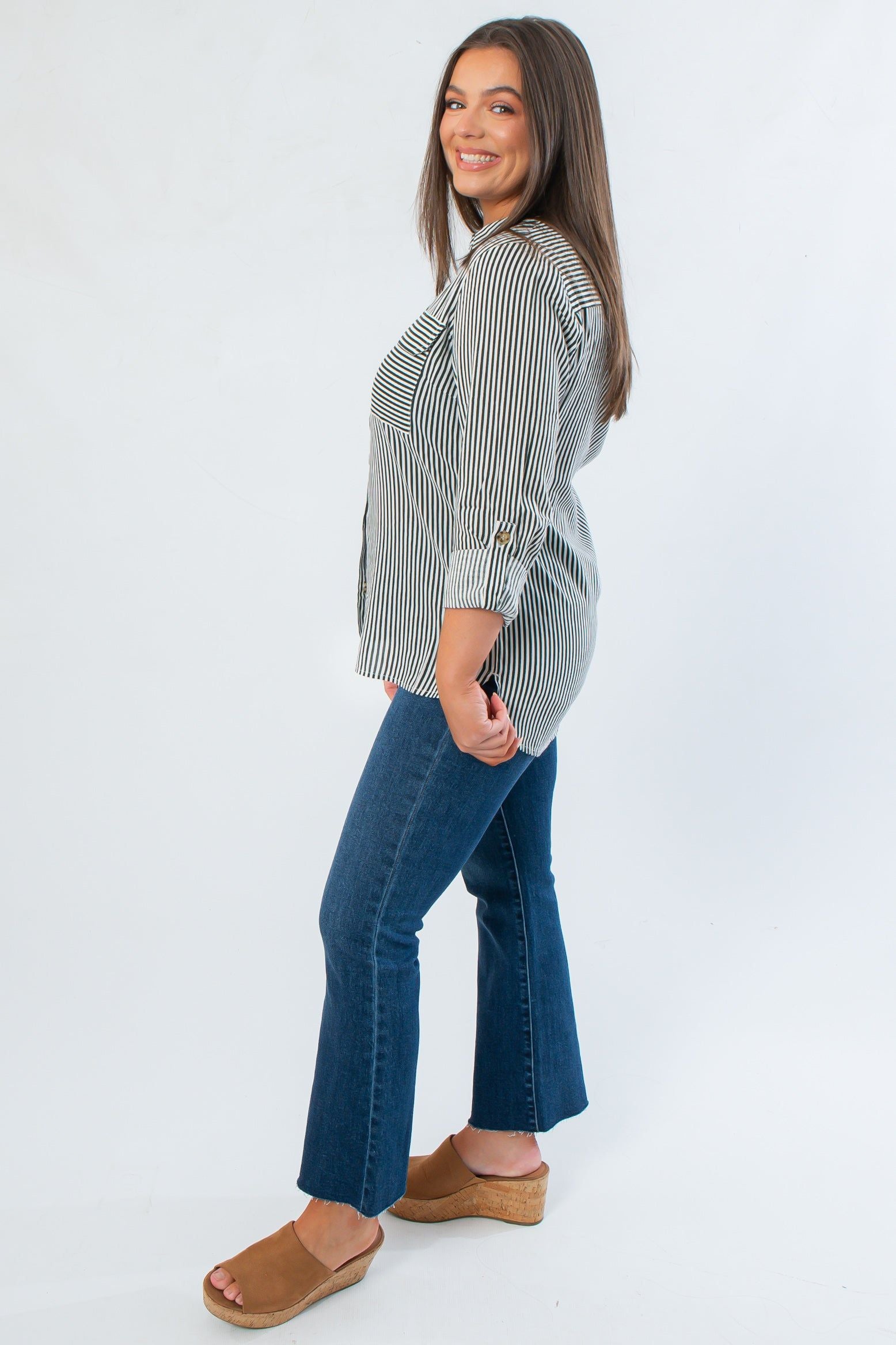 Side view of Dark Green Striped Button Down with rolled sleeves, highlighting its relaxed fit and vertical stripe pattern for fall layering.