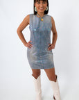 Woman smiling in iridescent coated denim dress, front pose with jewelry and styled hair