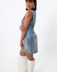 Back view of woman in iridescent denim dress, styled hair, and jewelry, white background