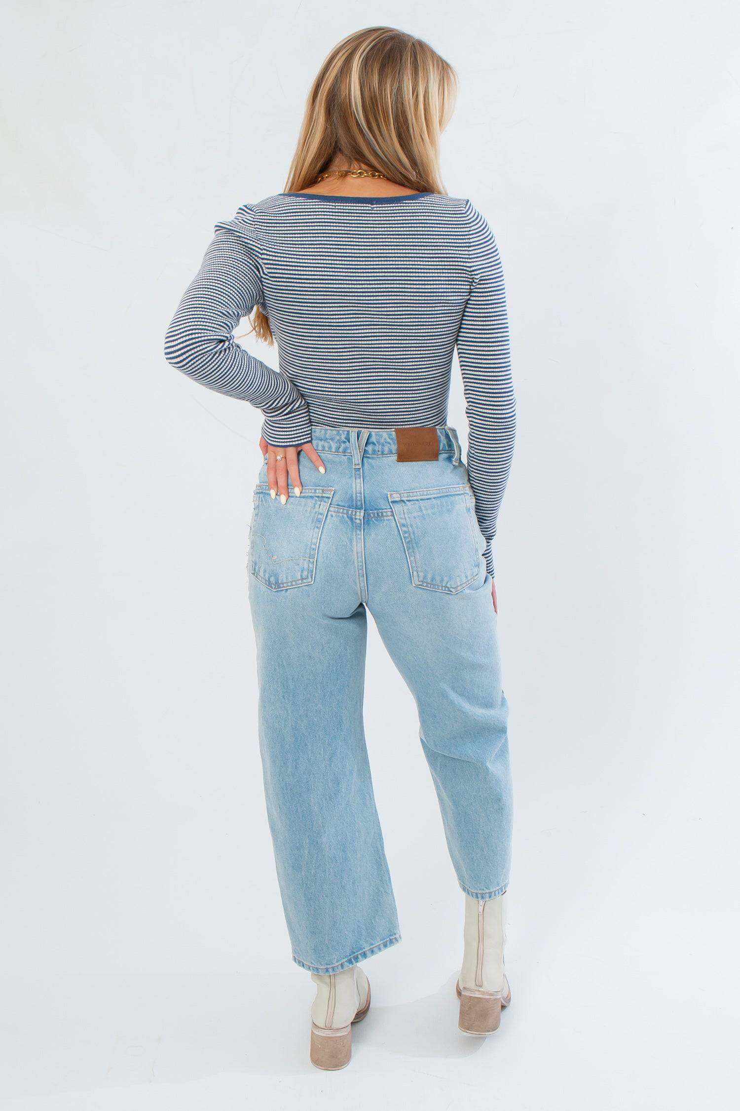 Back view of Before You Go Blue Stripe Long Sleeve Crop Top showing ribbed knit design and snug fit, paired with high-rise jeans and ankle boots.
