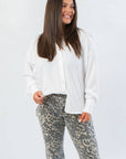 Rylee White Oversized Button Down Shirt with cuffed sleeves and relaxed fit, styled with leopard print pants for a chic workwear look.