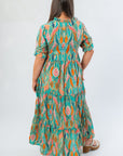 Back view of Mahi Maxi Dress in sea foam green with bold multicolor pattern, elastic waist, and ruffled tiered layers for a flattering fit.