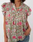 Close-up of woman in mint floral blouse with ruffled sleeves and button details