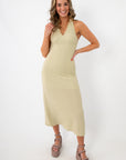 woman in beige textured halter midi dress with chunky platform sandals and gold jewelry
