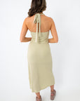 side view of woman in sage textured halter midi dress with wavy hair