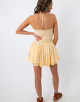 Woman in yellow lace trim dress with back view, standing with hand on hip, white background