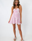 Woman in pink and white abstract mini dress with white background and jewelry