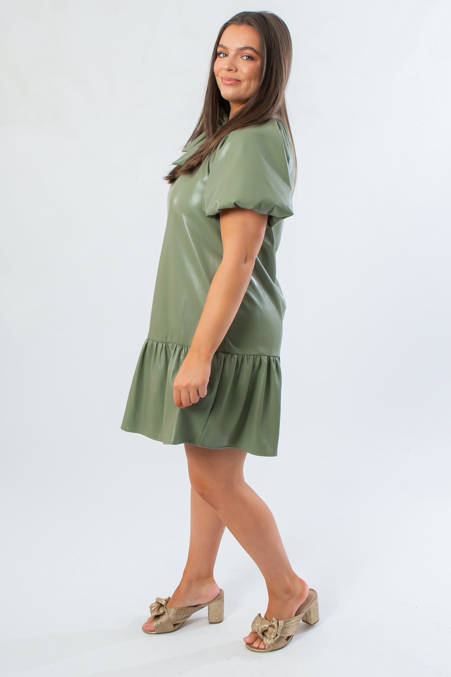 Side view of THML Olive Puff Sleeve Faux Leather Mini Dress showcasing relaxed fit and gathered hemline for a chic fall look.