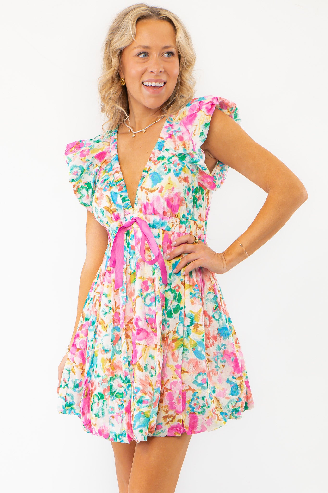 Close-up of Meet Me in Santorini Aegean Garden Dress highlighting flutter sleeves, deep neckline, and vibrant pink waist tie.