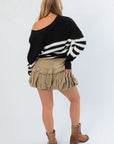 Back view of VM Cardigan in Black and White Stripe showing off its relaxed fit and bold horizontal stripes, styled with a ruffle skirt.