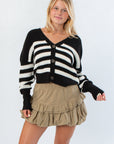 VM Cardigan in Black and White Stripe with oversized buttons and drop shoulder fit, styled with a khaki ruffle mini skirt for a chic fall look.