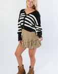 VM Black and White Stripe Cardigan styled for fall with a khaki ruffle skirt and brown boots, ideal for layering in cooler weather.